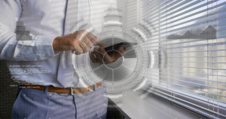 Standing businessman in blue shirt and necktie tapping smartphone by office window with HUD overlay. Phone, workspace, urban, daylight, code, augmented, dashboardの写真素材