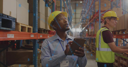 Inspecting supervisor in yellow hard hat and ID badge holding tablet, checking long warehouse aisle....