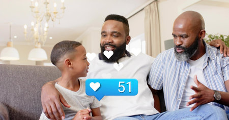 Smiling family trio sitting close on gray sofa in bright living room, with white heart overlay....