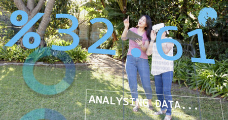 Pointing daughter guiding mother, holding tablet and headset, in jeans in garden with AR graphics....