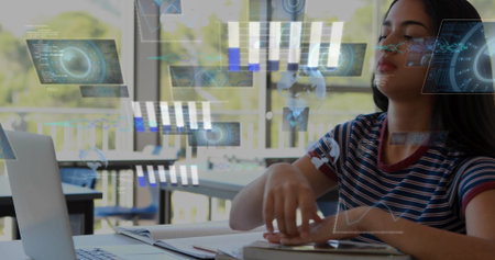 Studying student in striped tee reaching for notebook at library table, with laptop and AR overlay....