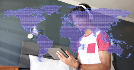 Teen in white red T-shirt wearing headphones tapping tablet at bedside, with purple map overlay....