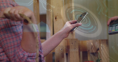 Showing smartphone, customer in plaid shirt paying at market stall with wooden pallets, reader HUD. Contactless, handheld, rustic, warm, vendor, shopfront, closeupの写真素材