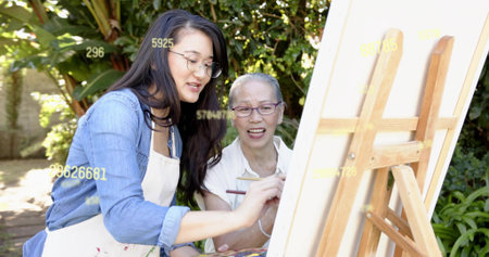Painting denim instructor in apron guiding student in blouse by wooden easel, canvas, copy space....