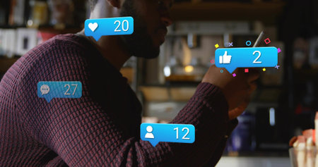 Scrolling man in maroon sweater and glasses holding smartphone at cafe counter, with notifications....