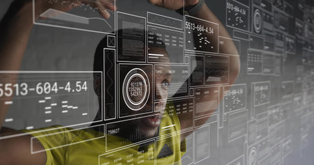 Interacting man wearing yellow shirt and watch touching transparent display at tech lab with HUD....