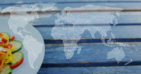 Displaying faint world map centered on worn blue slats, with plate holding cucumber, pepper, tomato....