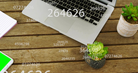 Sitting silver laptop centered on wood table, showing phone, notebook, plants, numeric overlays....