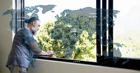 Leaning senior rolled-sleeves using tablet at sill by black window with AR map, trees, copy space....