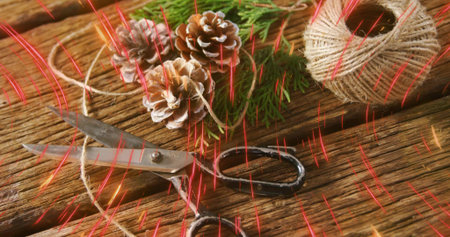 Lying pair of vintage scissors on diagonal rustic tabletop with jute twine, pinecones, red streaks....