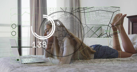 Lying woman wearing white long-sleeve and blue shorts checking laptop in bedroom, HUD overlay....