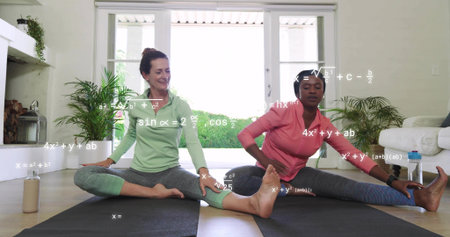 Stretching two women wearing pink and green tops on black mats in living room. Wellness, fitness,...
