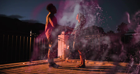 Holding hands couple standing on rooftop deck dusk, candles glowing, magenta haze, casual wear....