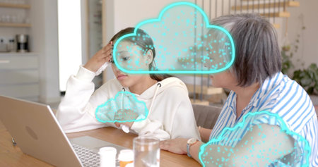 Helping mom in striped shirt supporting teen in hoodie at kitchen table, laptop, pills. Family, caregiver, student, computer, anxiety, comfort, cozyの写真素材