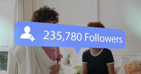 Sitting two women wrapped in white blanket, chatting in bedroom with blue overlay. Cozy, friendship,...
