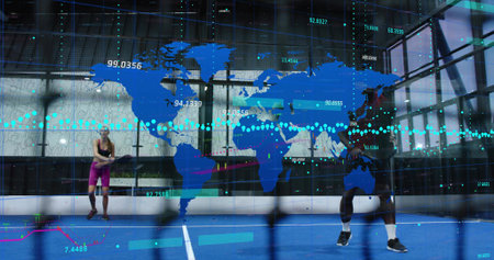 Competing two athletes in sportswear swinging rackets on blue court in glass gym, with data overlay....