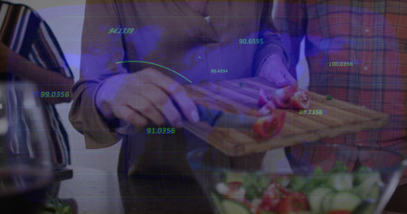 Slicing halved tomatoes, pair wearing light shirt and red or green plaid cutting on board in...