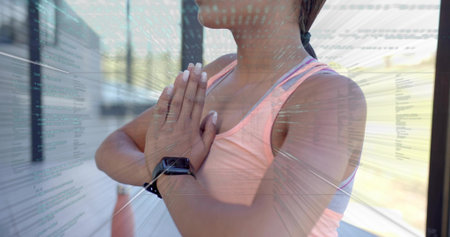 Standing adult woman pressing hands at chest in sunny studio, pink tank, smartwatch, code overlay....