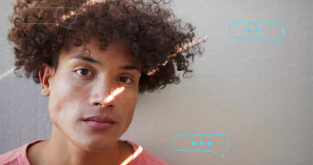 Leaning man gazing at camera by wall showing speech bubbles, sun streak, salmon tee, copy space....