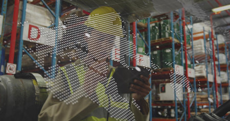 Inspecting, worker holding tablet in warehouse with yellow hard hat, hi vis vest, world map overlay....
