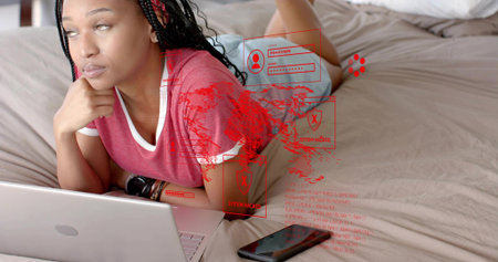 Lying woman in red ringer tee and shorts on bed using laptop, smartphone with holographic overlay....