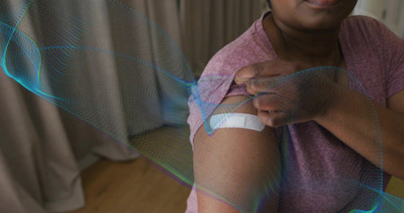 Pulling sleeve, mature woman wearing mauve tee showing upper-arm bandage by curtains, copy space....