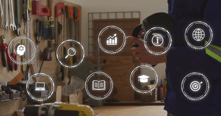 Man wearing hi-vis jacket holding disc, checking at shop bench with pegboard, icons, copy space....
