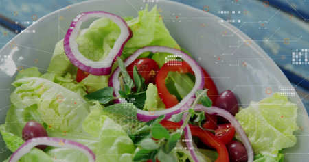 Displaying ceramic bowl with lettuce, tomatoes, onion rings and olives on blue table. Salad,...
