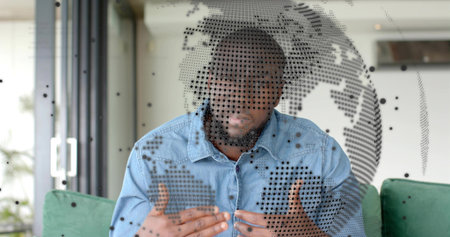 Speaking man gesturing, presenting at home with couch, glass door, globe overlay, denim shirt....