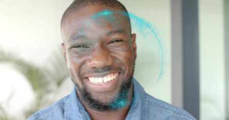Smiling man wearing denim shirt showing metal braces and teal powder on face in studio. Portrait,...