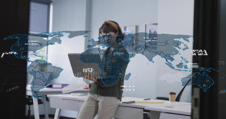 Holding laptop, talking on smartphone, woman in cardigan and glasses leaning at desk with HUD map....