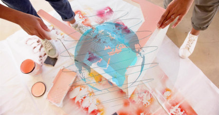 Positioning women in jeans, sneakers adjusting acetate globe over drop cloth with roller, paint can....