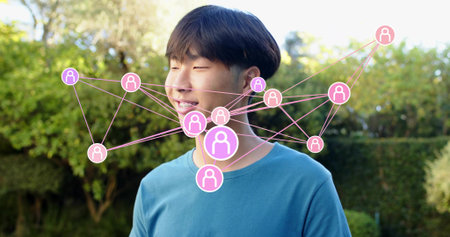 Smiling Asian male wearing teal crewneck tee standing in garden, with pink node overlay. Individual,...