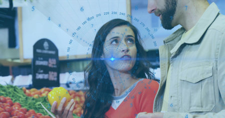 Holding red-top white-collar woman selecting yellow pepper in produce aisle, chalk sign. Couple,...