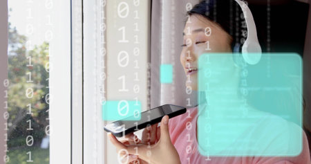 Speaking Asian woman holding smartphone to mouth at home, wearing headset, pink top, binary UI....