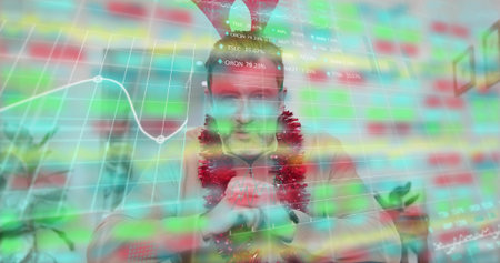 Sitting mature man in red sweater, tinsel and cone hat in office displaying market-data overlay....