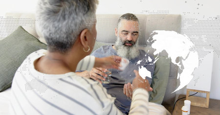 Offering woman wearing stripes handing medicine cup to man on bed with pill bottles. Caregiving,...