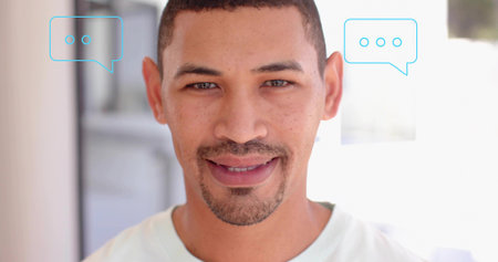 Smiling man wearing light tee facing camera in bright corridor, with chat bubbles and window. Male,...