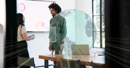 Talking bearded man wearing green shirt presenting charts in meeting room with laptop and tablet....