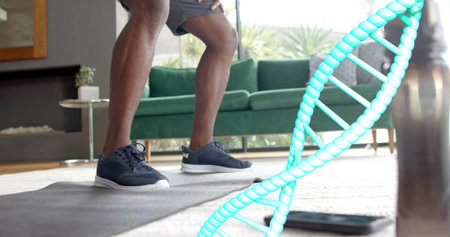 Squatting, lower-body in gray shorts, navy sneakers on gray mat at home with DNA helix, phone....