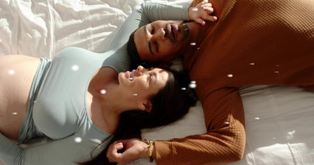 Lying two women facing each other on bed, displaying teal crop and brown textured tops, bracelet....