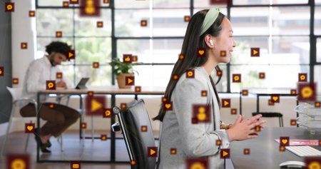 Talking Chinese woman in gray blazer headband gesturing on call open office earbuds floating icons....