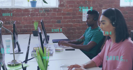 Typing woman wearing pink top, black headset working at open office desk, with monitors, copy space....