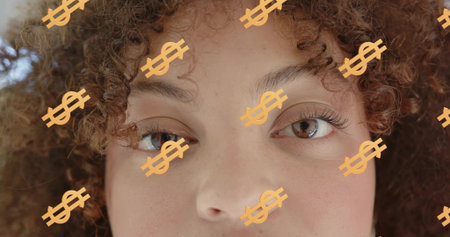 Gazing woman with curly hair staring at camera in studio headshot, with orange dollar-sign overlays. Closeup, portrait, freckles, eyes, skin, soft, lightingの写真素材