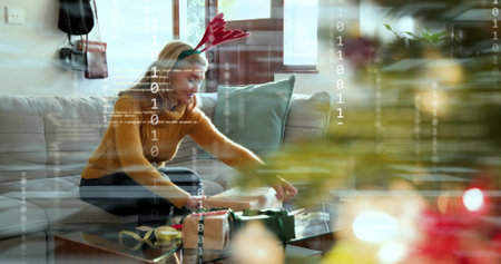 Wrapping gifts on coffee table at home, woman wearing mustard sweater and antlers. Presents,...