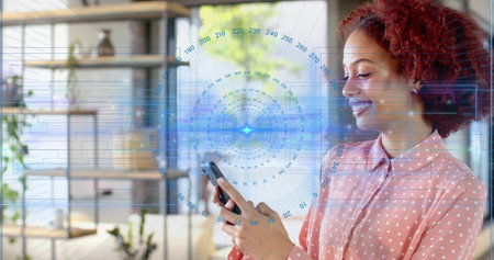 Holding smartphone woman in pink polka blouse viewing screen in office with HUD overlay, copy space....