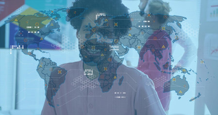 Presenting man wearing light pink shirt pointing at digital world map overlay in office, glass wall....