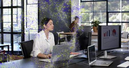 Working woman in white blouse checking laptop and external monitor at open-plan office, with notes....