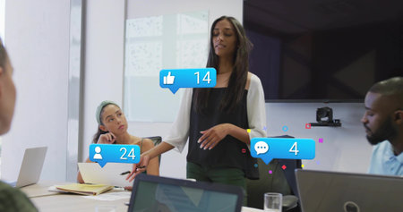 Speaking woman leading meeting in conference room, wearing black top, with laptops and overlays....