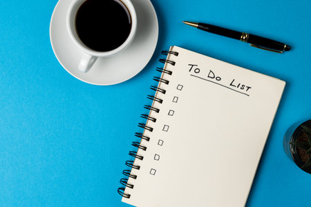 Image of notebook with to do list and copy space, coffee and pen on blue surface. Business, working...